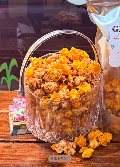 Clear glass bowl filled with popcorn on a wooden surface, with a bag of popcorn in the background.